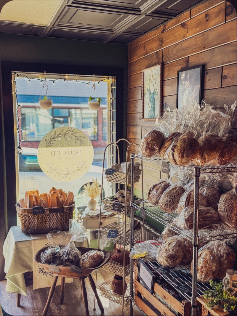 Double B Sourdough bakery interior with shelves of bread, pastries, and a view of the street outside through a large window.