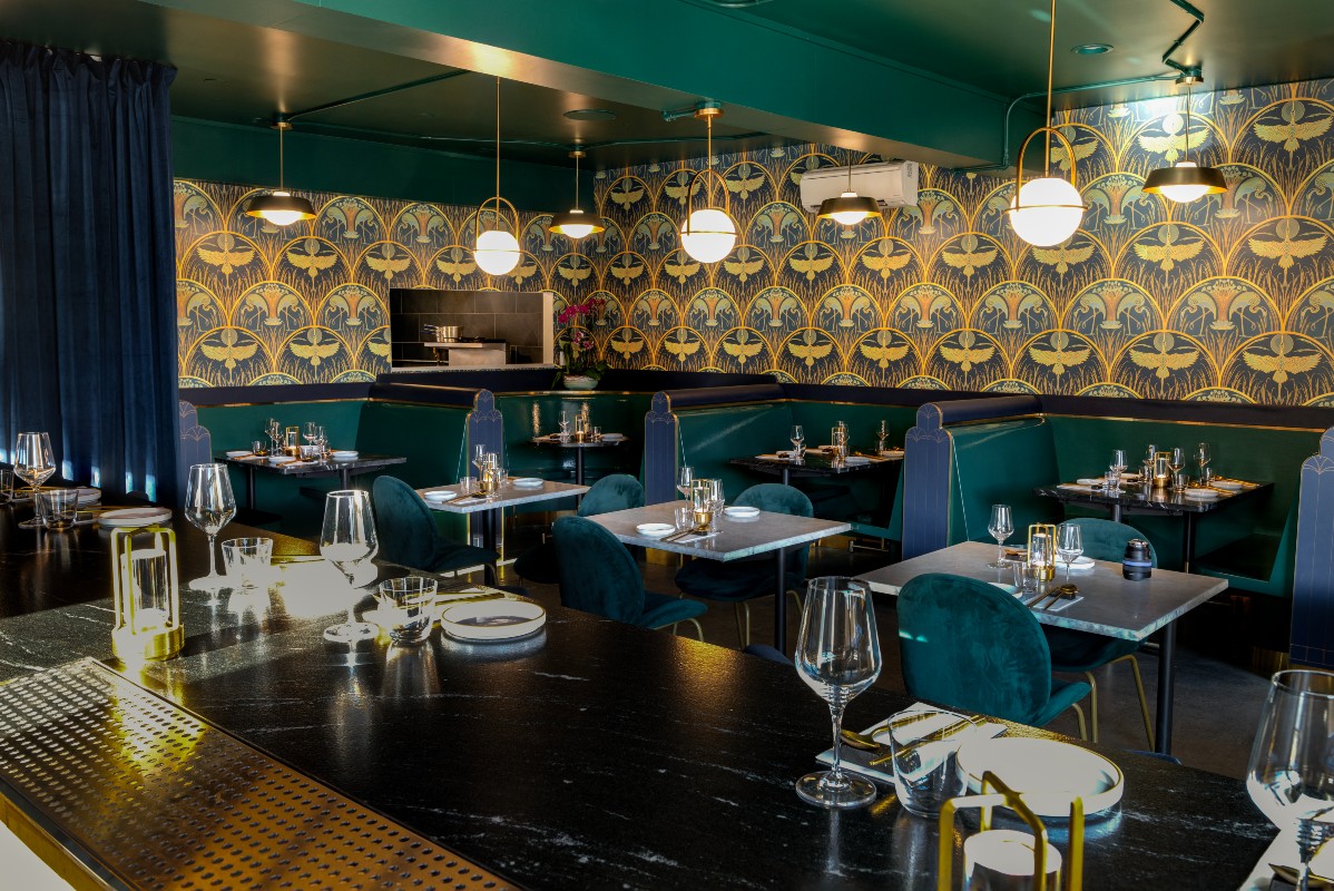 The elegant Threshold restaurant interior featuring dark tables, plush seating, stylish lighting, and patterned wallpaper, creating a sophisticated dining atmosphere.