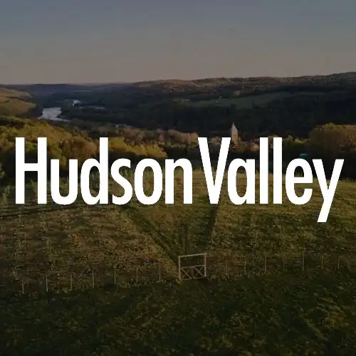 Aerial landscape of Hudson Valley, featuring lush greenery, hills, and a serene river in the background.