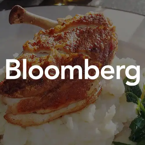 A plate of crispy roasted chicken served over a bed of rice with a side of greens.