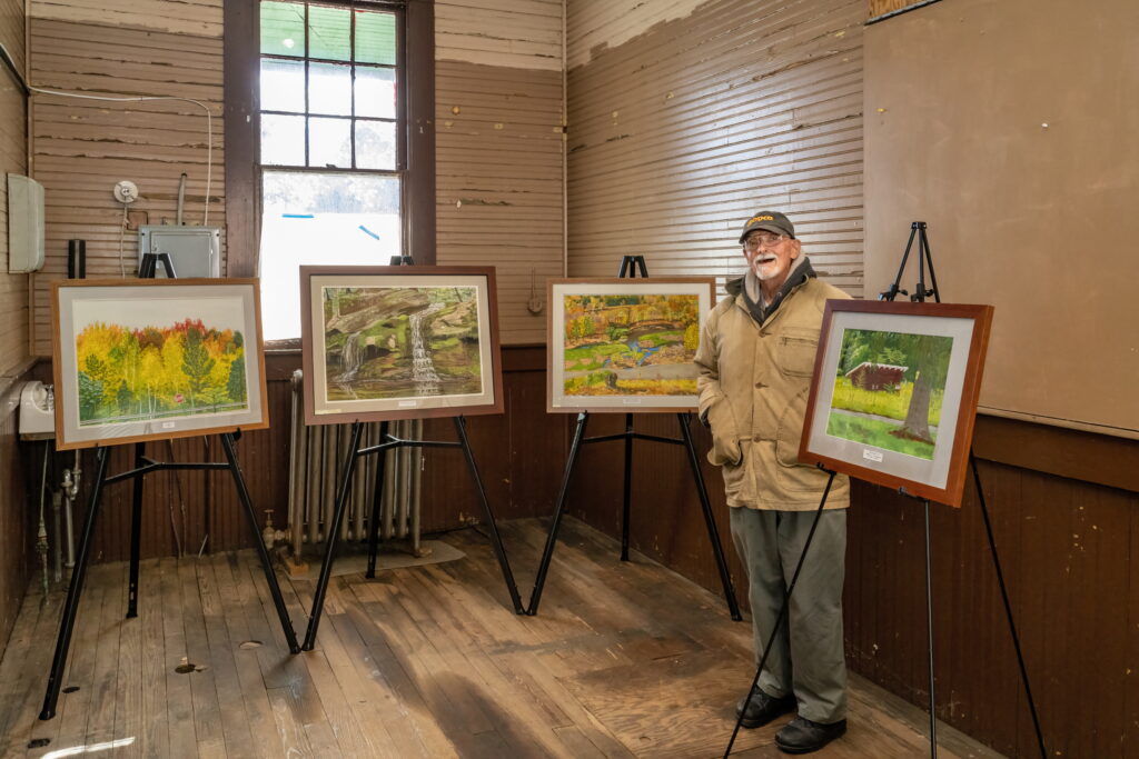 A Catskills artist with his paintings in a gallery. 