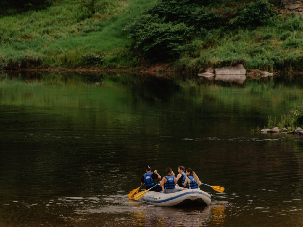 A group of people and guide raft on a river in the Sullivan Catskills. 