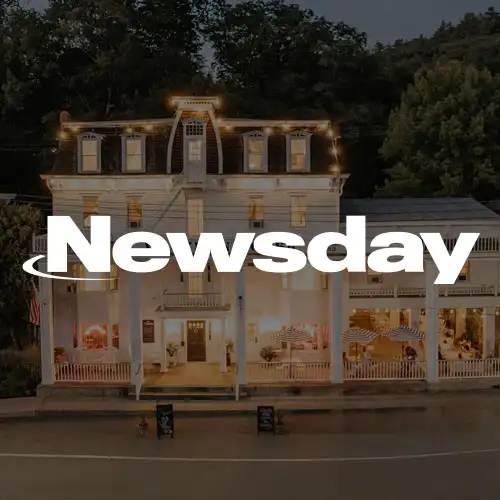 A beautifully lit, historic building with a porch, surrounded by trees and evening ambiance.