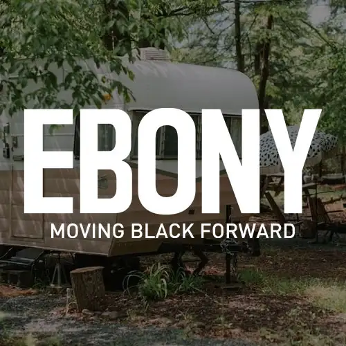 A vintage trailer surrounded by greenery, featuring prominent text reading 'EBONY' and a tagline 'MOVING BLACK FORWARD'.
