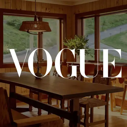 A cozy dining area with wooden decor, large windows showcasing greenery, and a stylish pendant light.