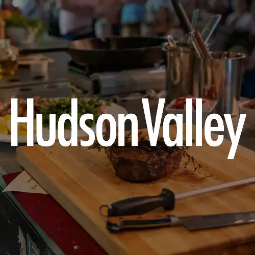 A rustic kitchen setting with a wooden cutting board showcasing a prepared dish, surrounded by fresh ingredients and cooking utensils.