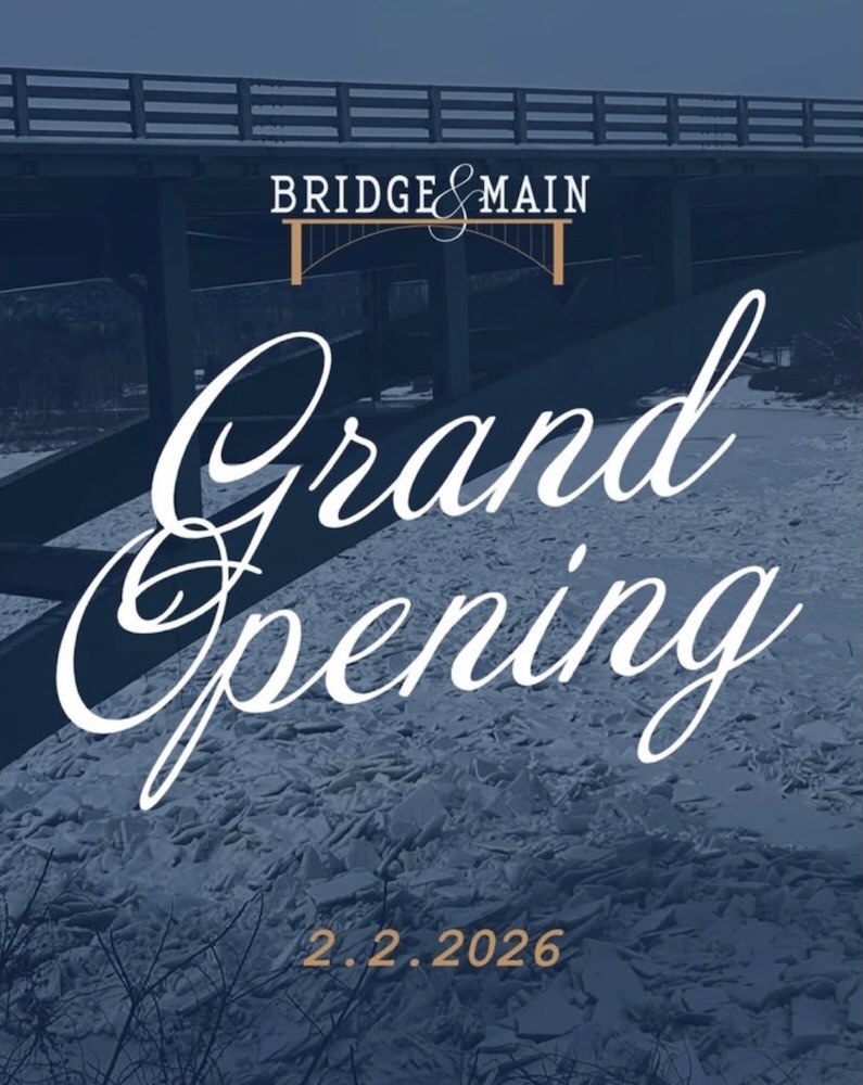 A promotional graphic announcing the grand opening of Bridge & Main on February 2, 2026, with a bridge and snowy landscape in the background.
