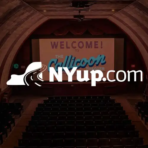 An empty theater with a large screen displaying a welcoming message, highlighting a venue or event.