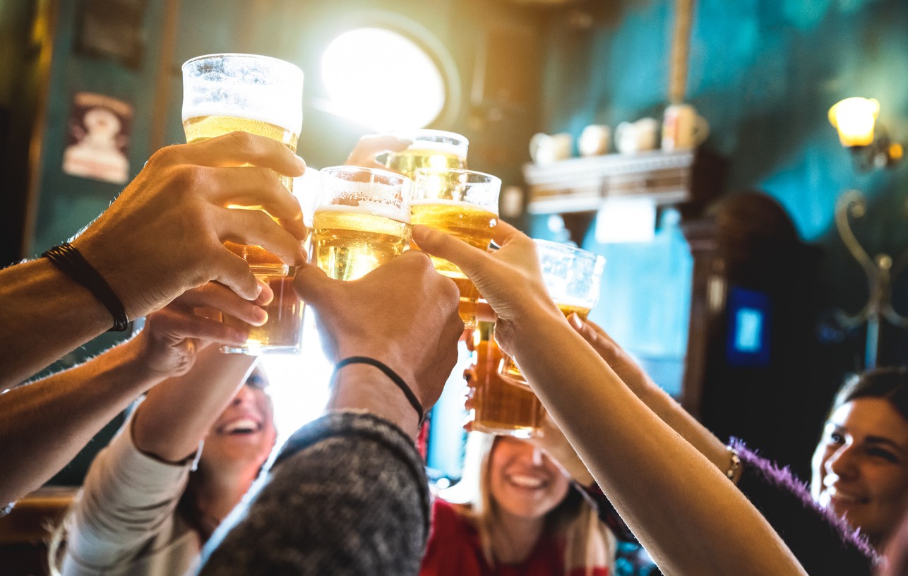 Friends raise a toast with beers at a local pub.