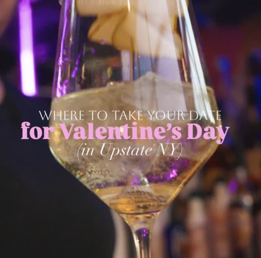 A close-up of a wine glass filled with a light beverage, surrounded by a festive ambiance, suggesting a Valentine's Day theme in Upstate New York.