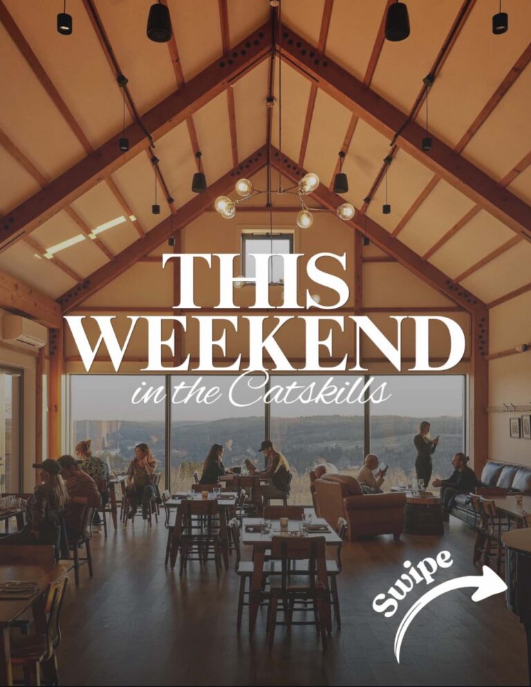 A cozy interior of a venue in the Catskills, featuring wooden beams, tables, and people enjoying their time with a scenic view.