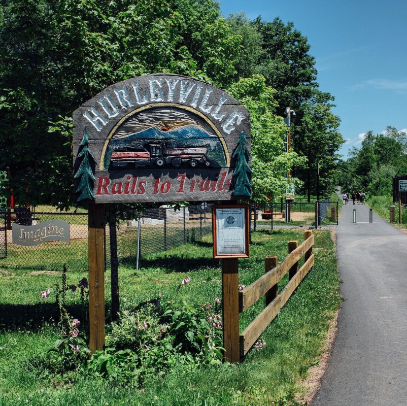 Hurleyville "Rails to Trails" sign alongside a paved trail. 