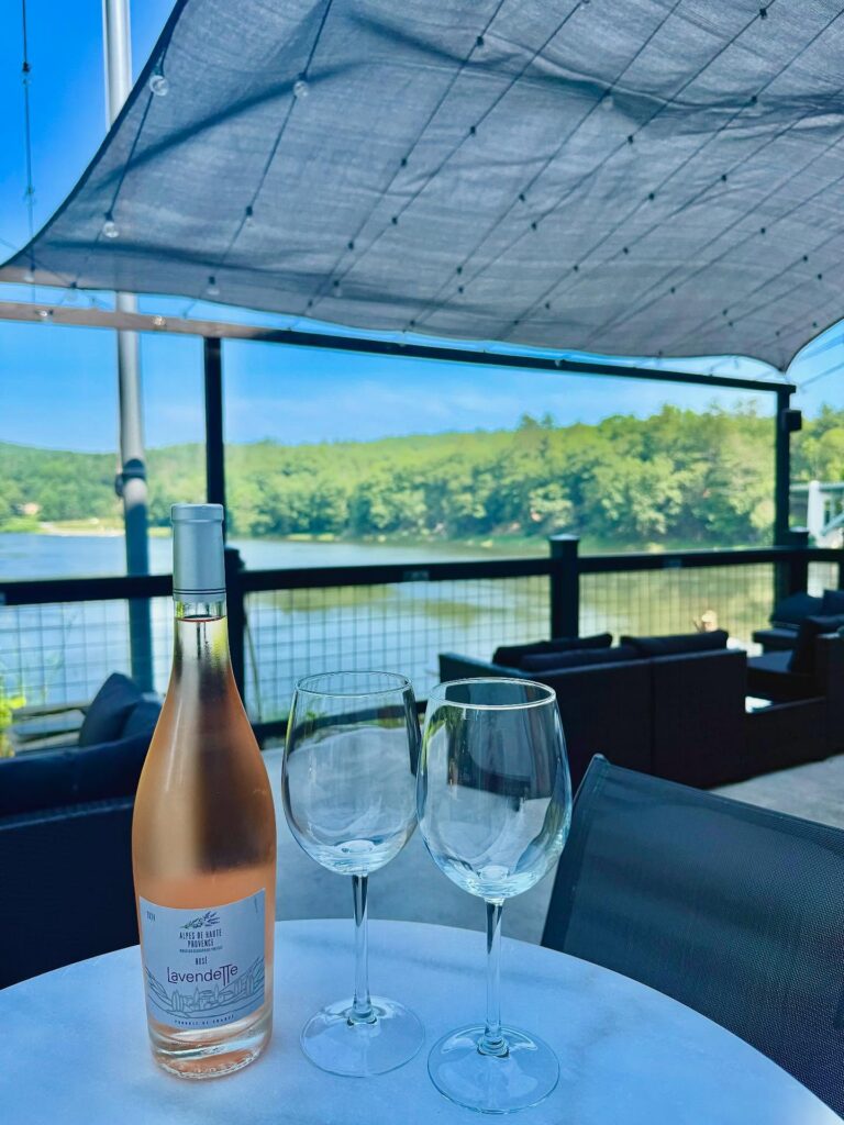 The outdoor patio with tables and lounge furniture and a bottle of Rose wine and two wine glasses at La Cigogne restaurant in the Sullivan Catskills.
